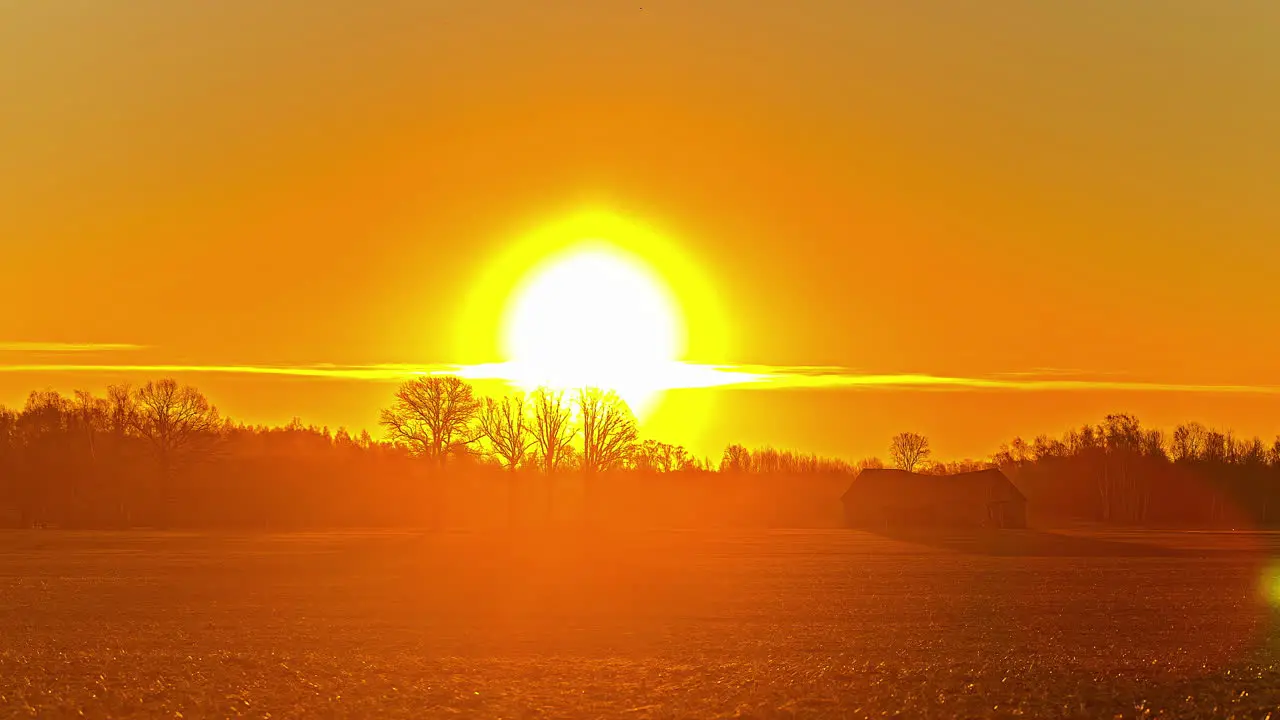 Static shot of sun rising over yellow sky in timelapse over the farmer’s pasture at dawn