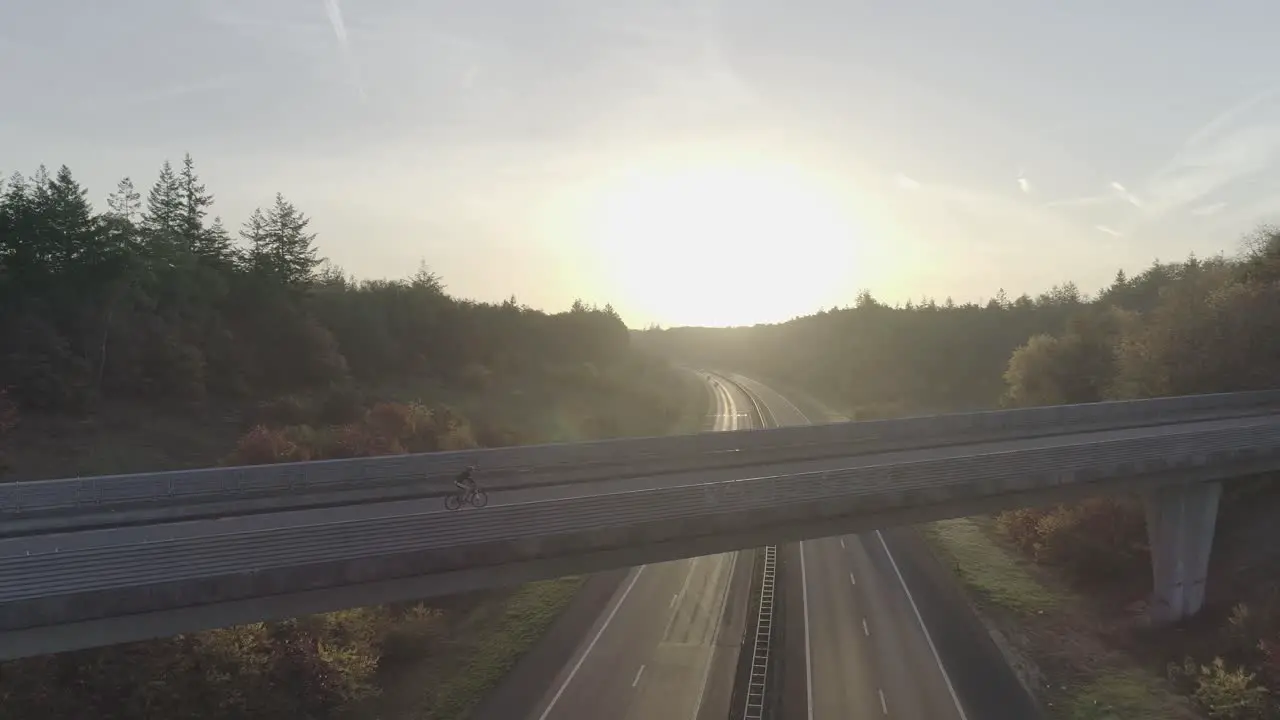 Mountainbiker riding over overpass with a sunrise or sunset