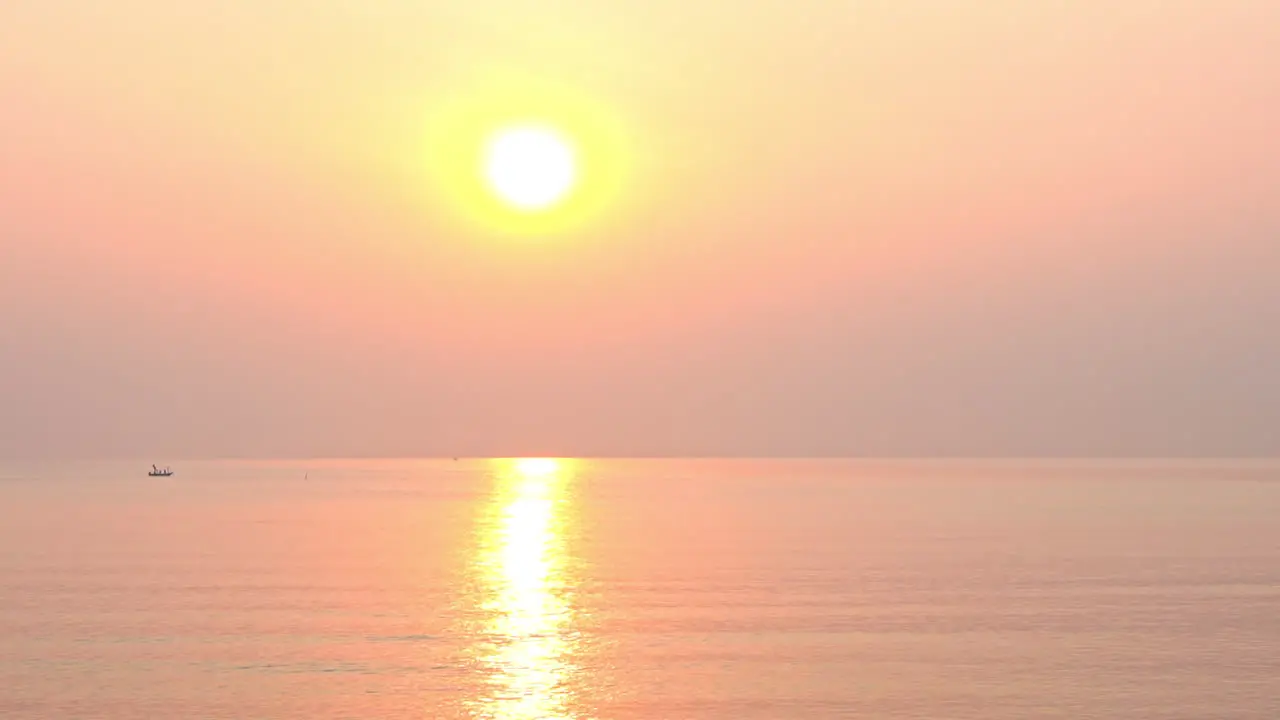 A dramatic pink and orange tropical sunset over the ocean waves