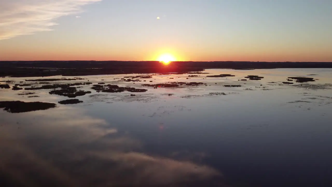 Crane drone view at sunset above a lake wetlands with a river in the background