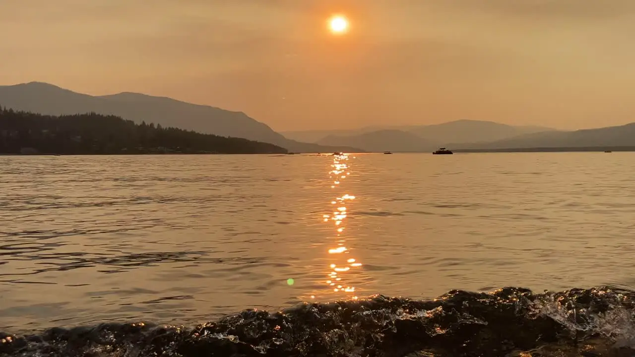 Hand-held shot of waves crashing on the shore of Shuswap Lake during sunset