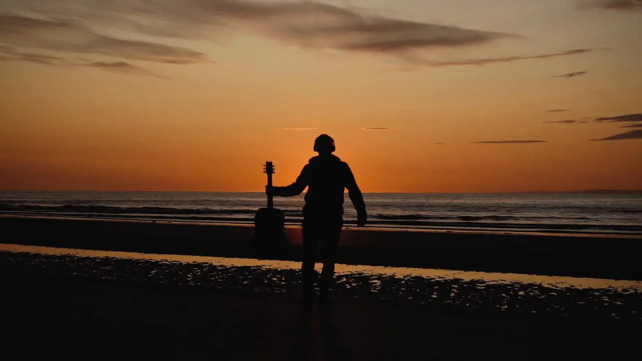 Man running with guitar in back sand beach at sunset-34