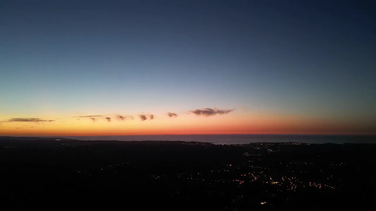 Atlantic coastline of Ascain France at dusk with lights illuminating the villages in the dark Aerial pan left reveal shot