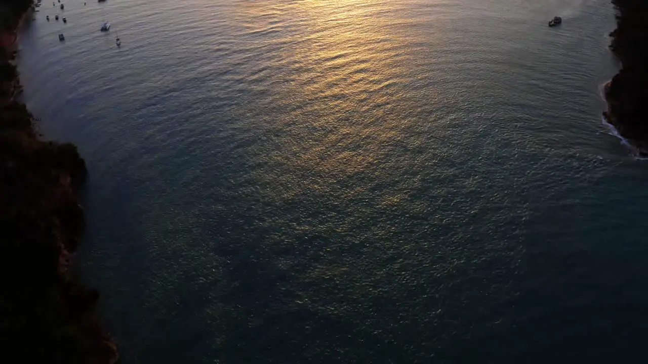 Stunning aerial drone top bird's eye view of a golden sunset reflecting onto a giant amazonian river in the tropical beach town of Tibau do Sol near Pipa in Northern Brazil on a warm summer evening