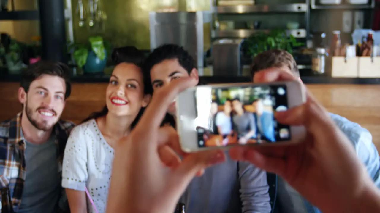 Woman clicking photo of friends on mobile phone