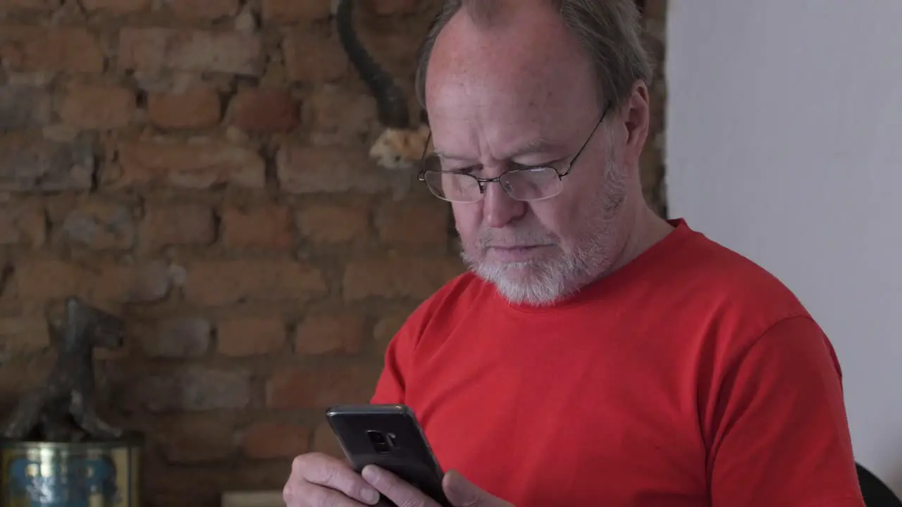 A middle aged man with a grey beard texting with his cell phone