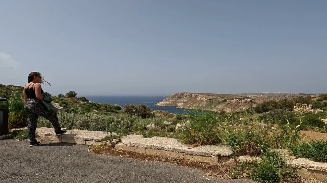 Gorgeous woman enjoys natural landscape of Malta island back view