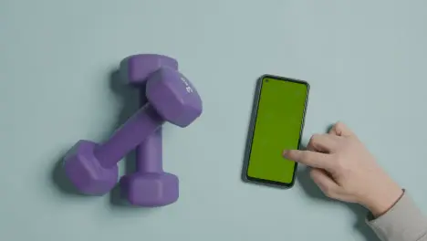 Overhead Fitness Studio Shot Of Exercise Dumbbell Weights With Hand Using Green Screen Mobile Phone 3