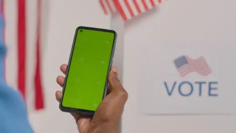 Close Up Of Man Holding Green Screen Mobile Phone In Front Of Ballot Box In American Election 1