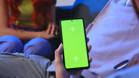 Close Up Of Woman With Green Screen Mobile Phone Sitting On Sofa At Home With Friends 1