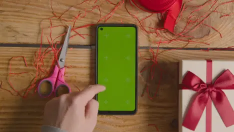 Overhead Shot Of Man Gift Wrapping Romantic Valentines Present In Box Using Green Screen Mobile Phone