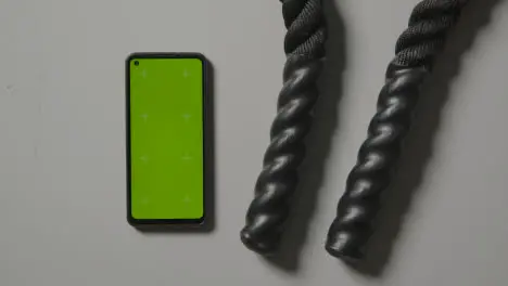 Overhead Studio Fitness Shot Of Person Using Green Screen Mobile Phone Next To Gym Battle Ropes On Grey Background 1