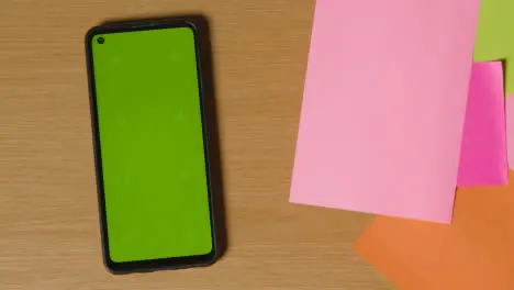 Business Concept Of Revolving Sticky Notes With Business And Financial Terms And Green Screen Mobile Phone