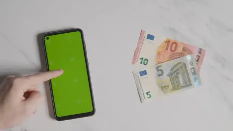 Overhead Currency Shot Of 10 And 5 Euro Notes Next To Person Using Green Screen Mobile Phone