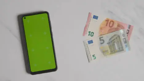 Overhead Currency Shot Of Hand Grabbing 10 And 5 Euro Notes Next To Green Screen Mobile Phone