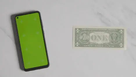 Overhead Currency Shot Of Hand Grabbing US 1 Dollar Bill Next To Green Screen Mobile Phone 1