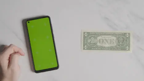 Overhead Currency Shot Of US 1 Dollar Bill Next To Person Using Green Screen Mobile Phone 1