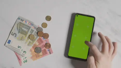 Overhead Currency Shot Euro Notes And Coins Currency Next To Person Using Green Screen Mobile Phone