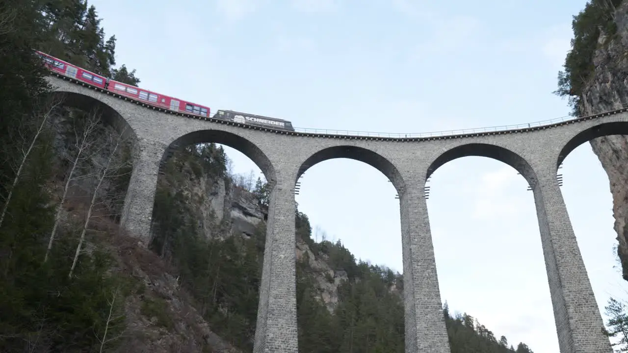 Traditional red Swiss panorama train passing on a stone bridge viaduct in Landwasser Brucke