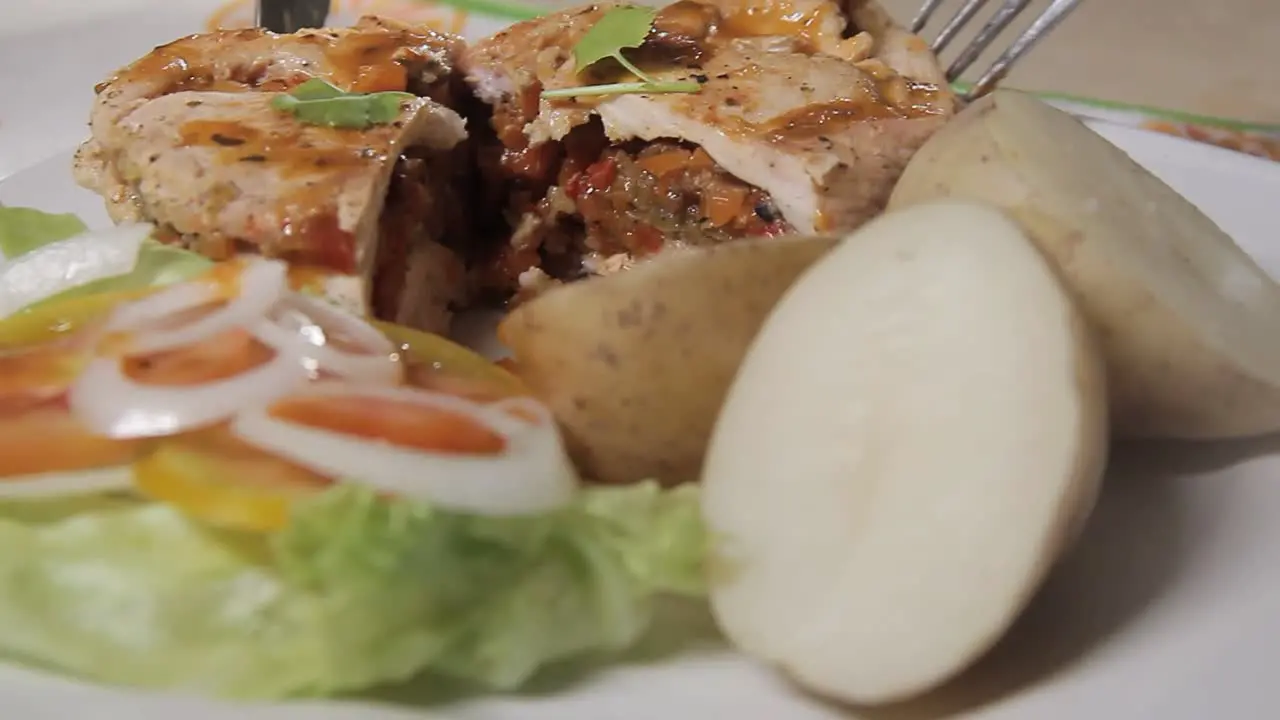 Close-up of chef cutting chicken with vegetables on white plate healthy home cooking concept