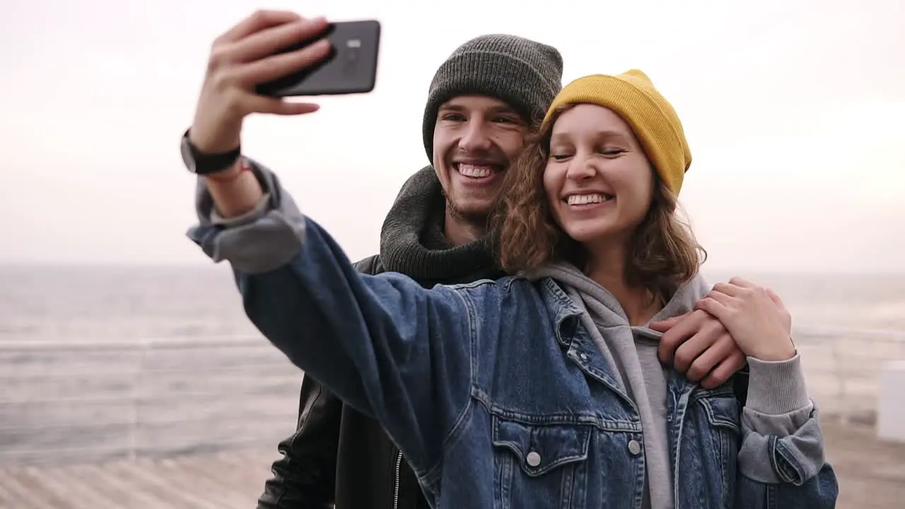 Happy Young Couple Taking Selfie By Mobile Phone Near The Seaside In Cloudy Day