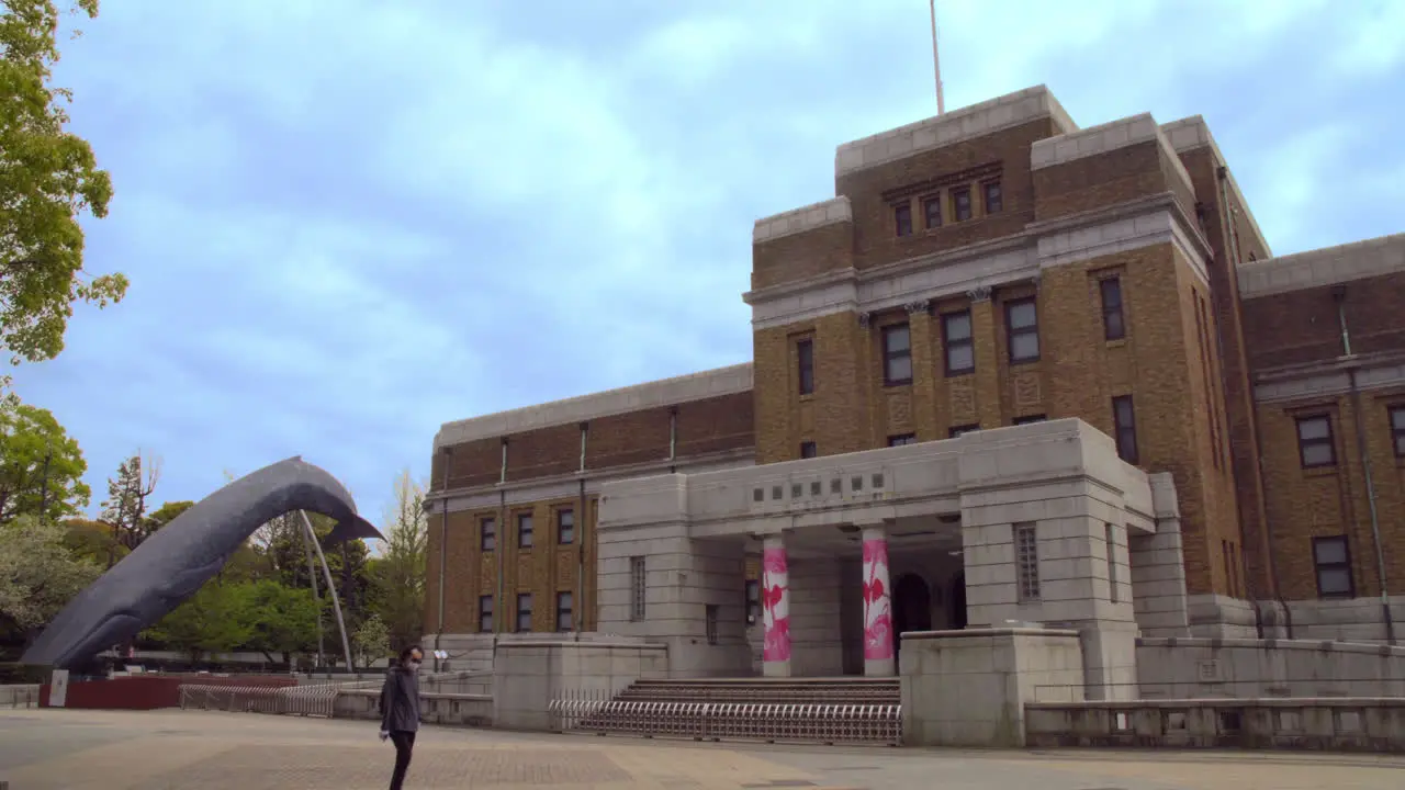 UENO NATIONAL MUSEUM OF NATURE AND SCIENCE TOKYO JAPAN circa April 2020 truck passing man with mask walking by in front of NATIONAL MUSEUM OF NATURE AND SCIENCE on quiet cloudy spring day