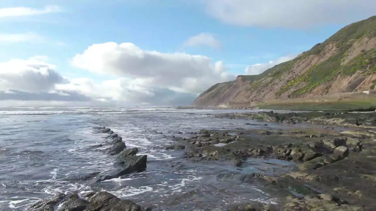 Jagged ocean rocks drone shot up to the mountains