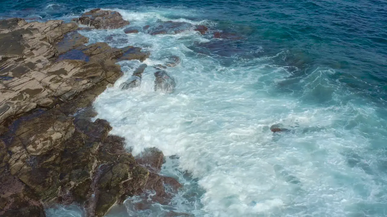 Drone shot of waves bounce on rocks at the beach