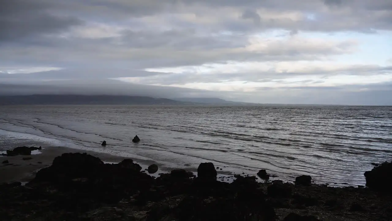 Timelapse of waves crashing on a sandy beach rocks on the seashore  cloudy weather in Dundalk Ireland