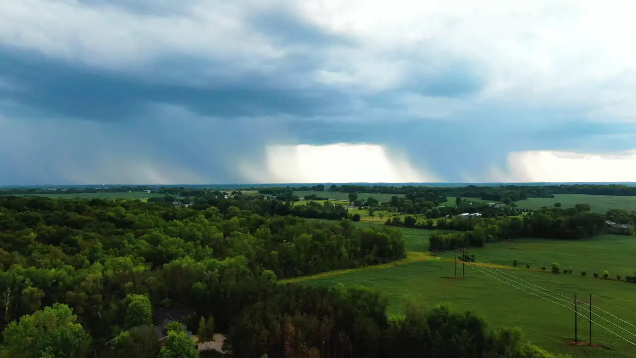 descending aerial Appleton Wisconsin lush green farmland with large storm cloud on the horizon