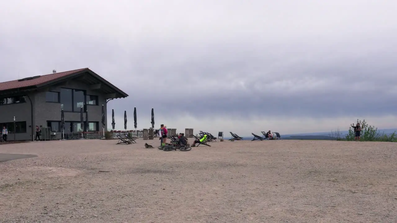 People relax on plateau next to a restaurant on cloudy day Hornisgrinde Germany