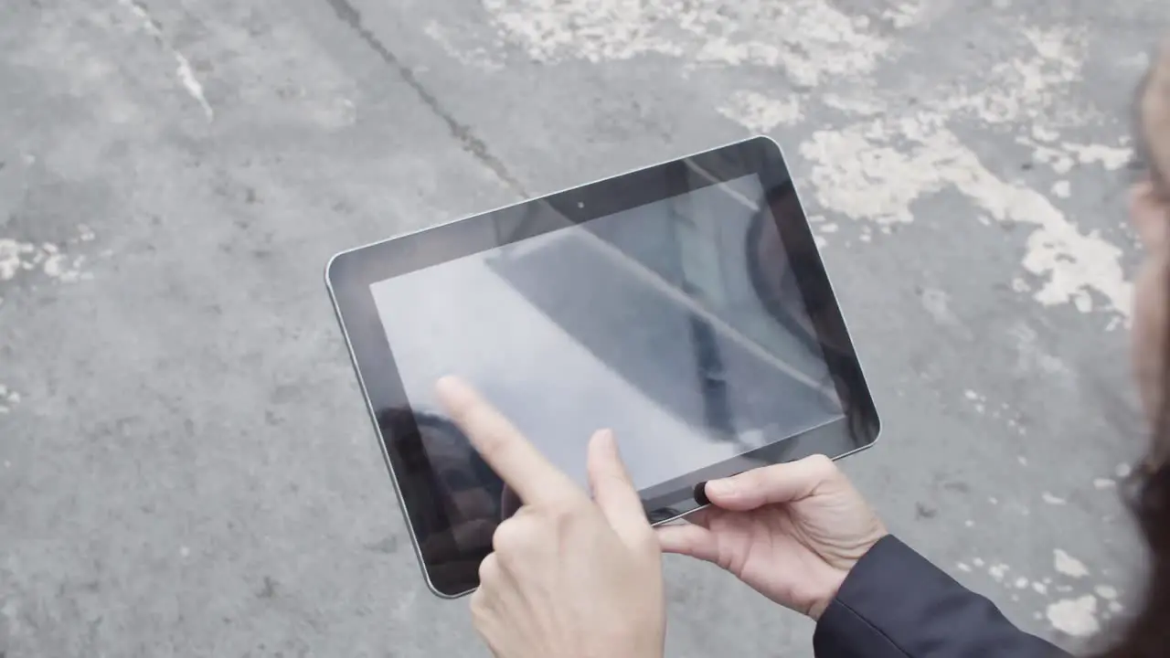 Two Female Colleagues Using Tablet And Watching Content Together While Walking Outside