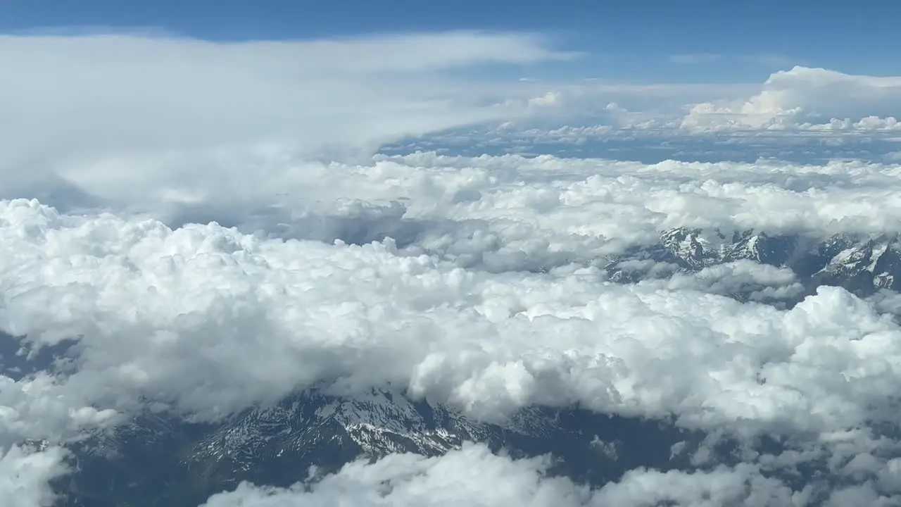 Aerial cockpit view pilot pov from a jet cockpit of the italian Alps mountains covered with some snow and white clouds