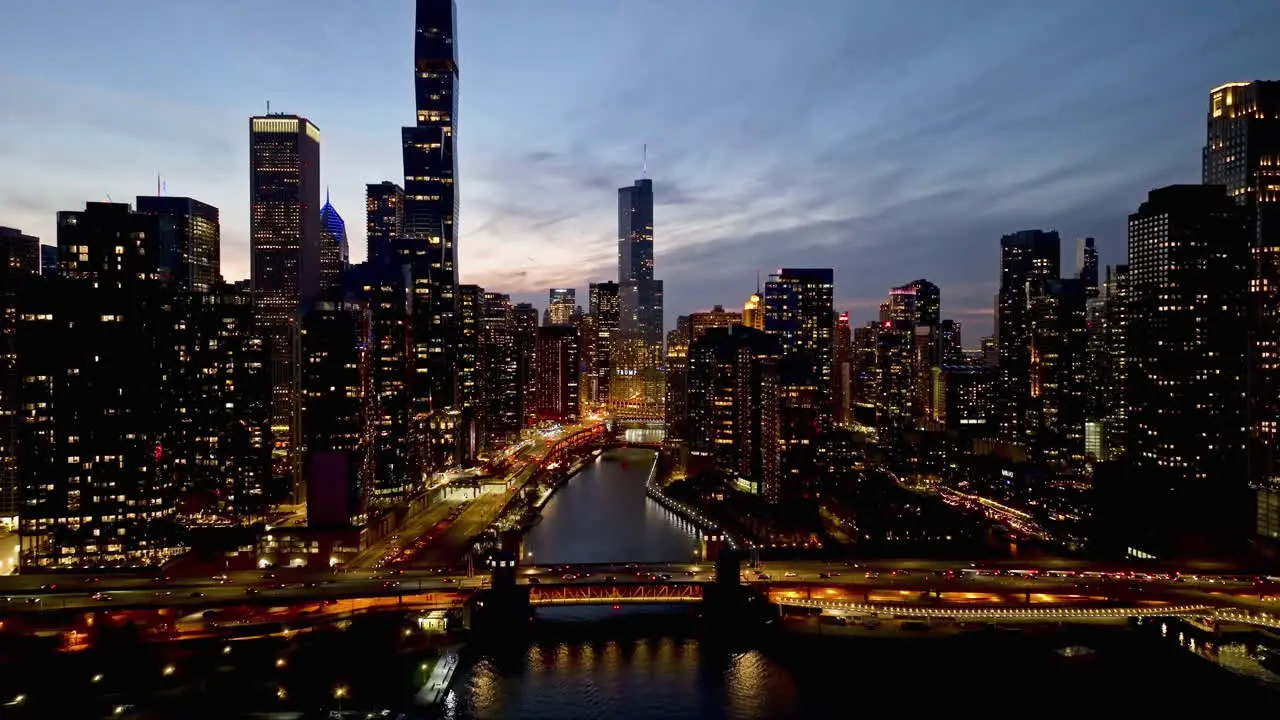 Aerial view following the Chicago Riverwalk in middle of skyscrapers fall dusk in USA