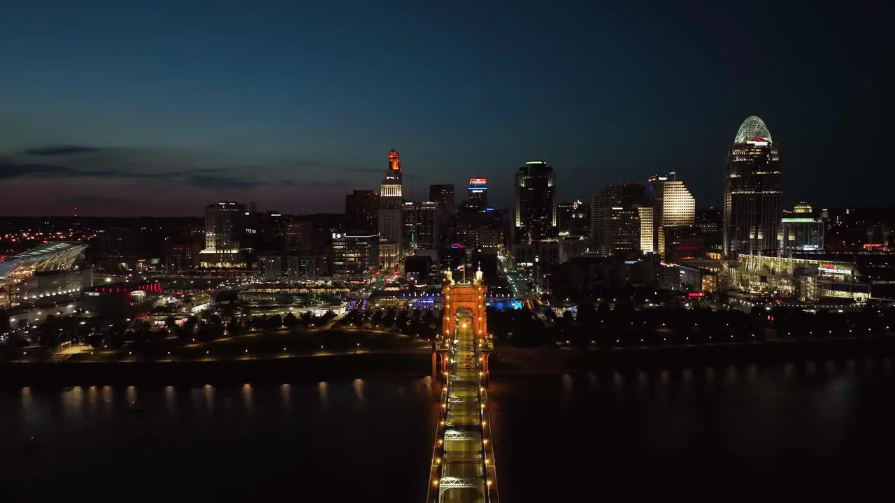 Aerial view over the Roebling Bridge with Cincinnati skyline in the background night in Ohio USA pull back drone shot