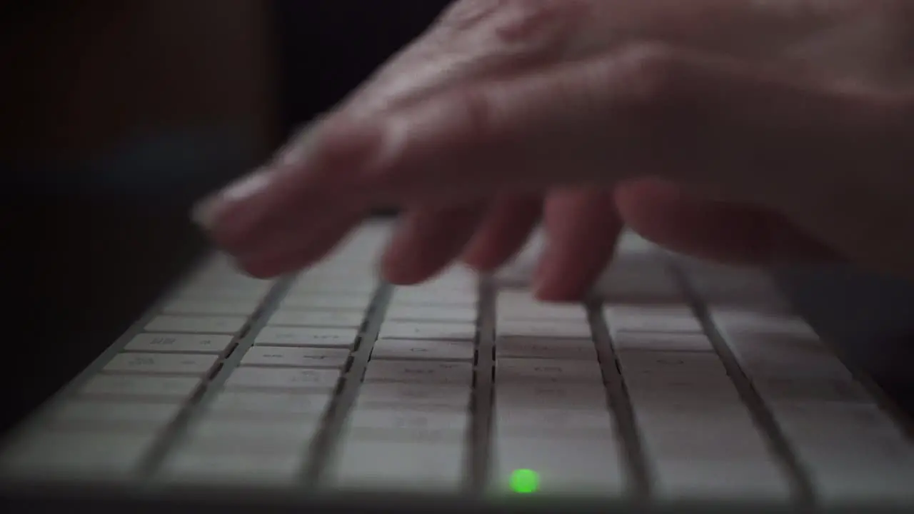 A hand writing on a keyboard while working in a Mac computer