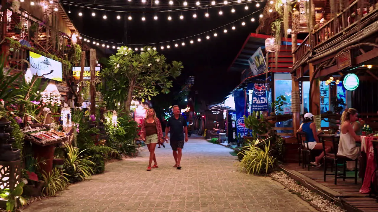 Couple on holiday walking in streets of Railay Bay at night Thailand