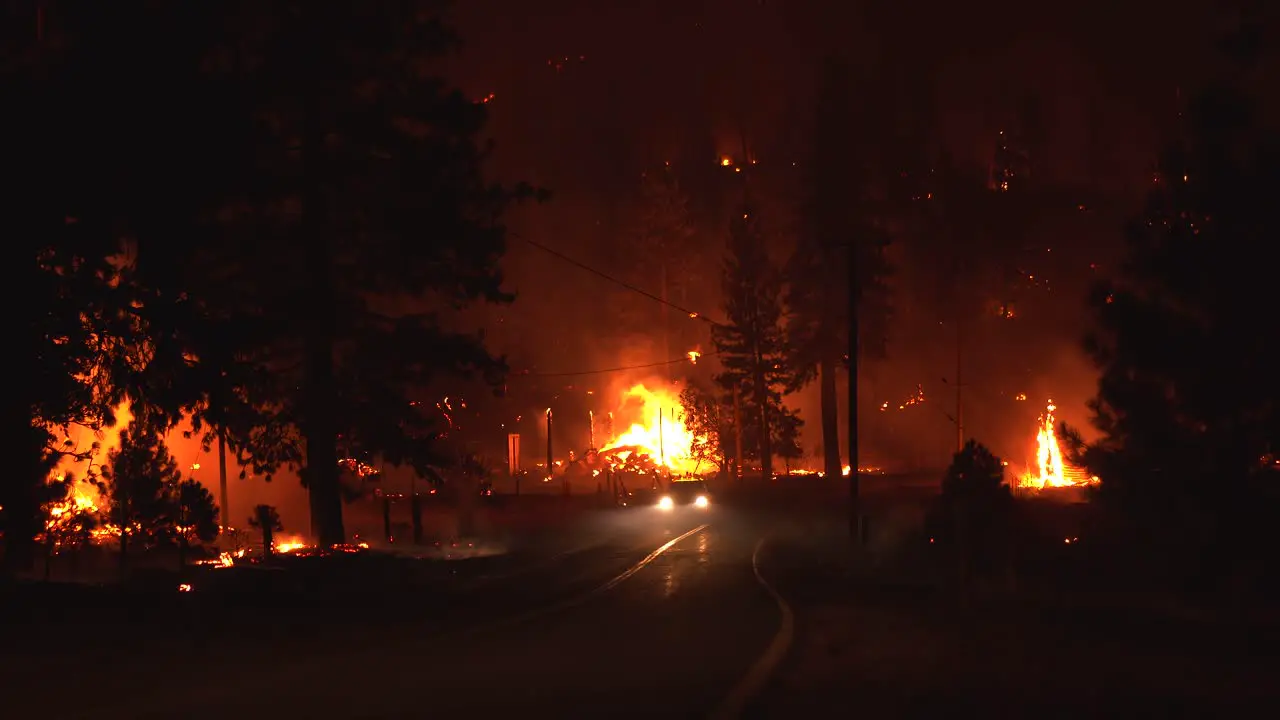 Firefighters driving on a road in middle of raging forest fires during nighttime