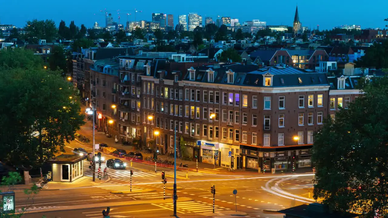 Day-to-night timelapse of a cityscape in Amsterdam with a busy intersection in the foreground a residential area and the Zuidas business district in the background