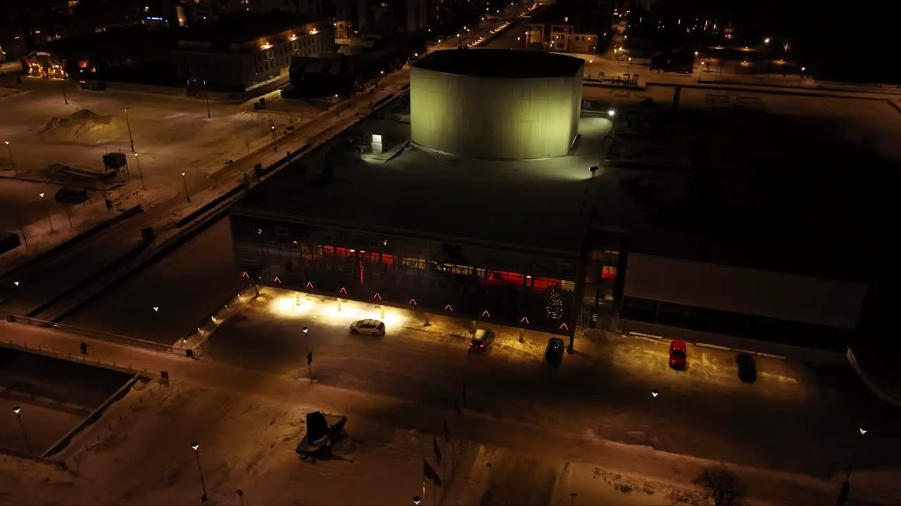 Aerial view orbiting the illuminated Oulu Theatre winter evening in Finland