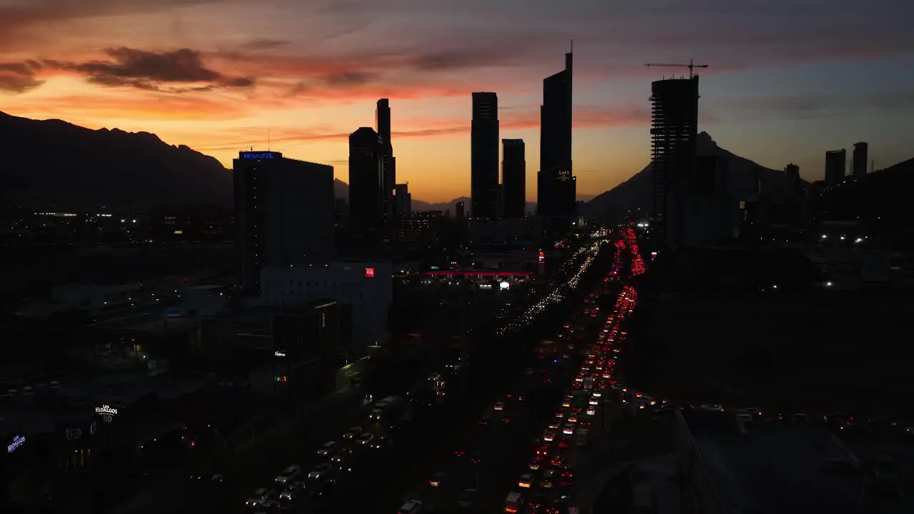 Aerial view over traffic towards silhouette skyscrapers in San Pedro Garza Garcia Monterrey colorful dusk in Mexico