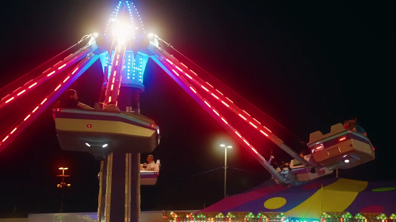 Neon lights flash as excited people enjoy a late night amusement park ride