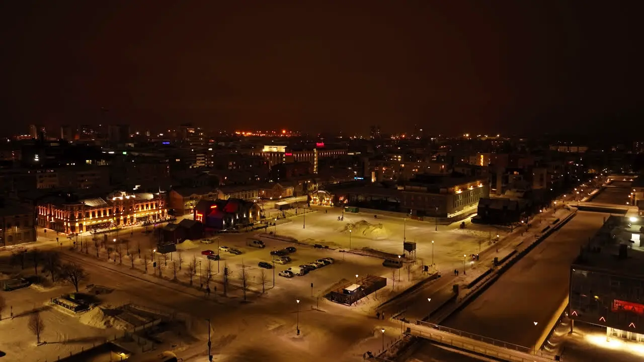 Aerial rising shot in front of the snowy market square winter night in Oulu Finland