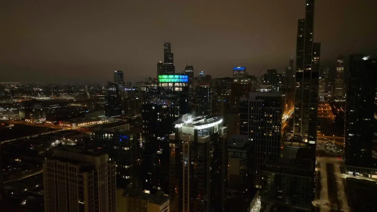 Aerial view in front of the illuminated The Paragon building cloudy night in Chicago USA Ascending drone shot