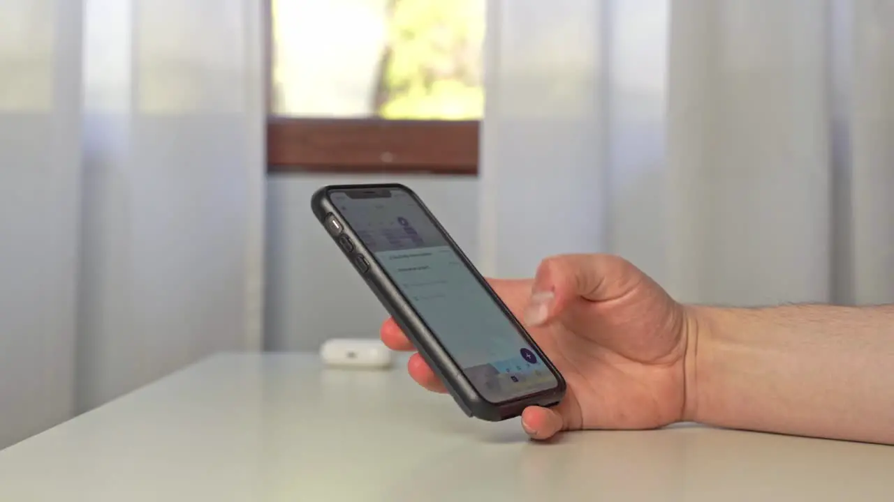 A young man uses his iPhone with a protective black bumper to thumb type a quick note to himself