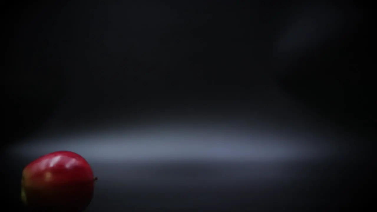 Slow Motion Hand Spinning a Ripe Red Apple on a Black Surface