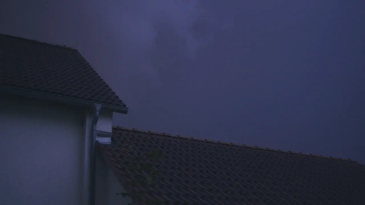 Medium white shot of a roof in an suburban neighborhood during a thunderstorm