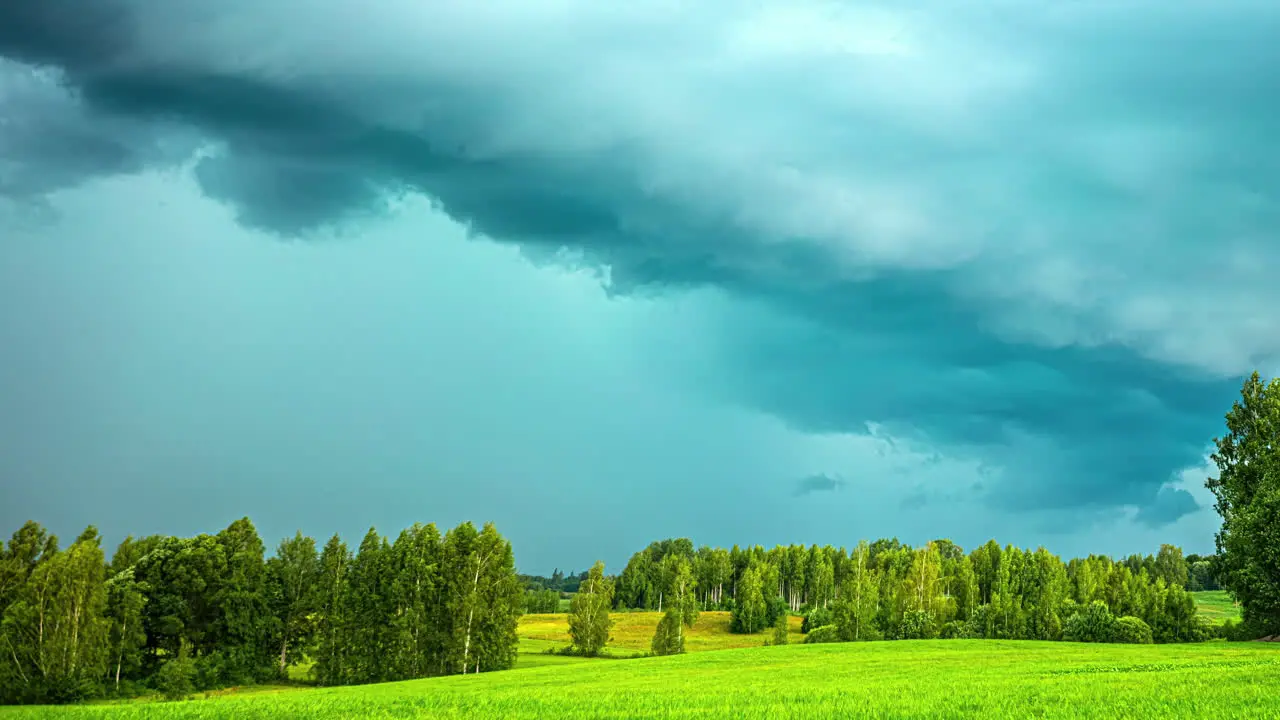 Threatening thunderstorm clouds glide past over a green landscape