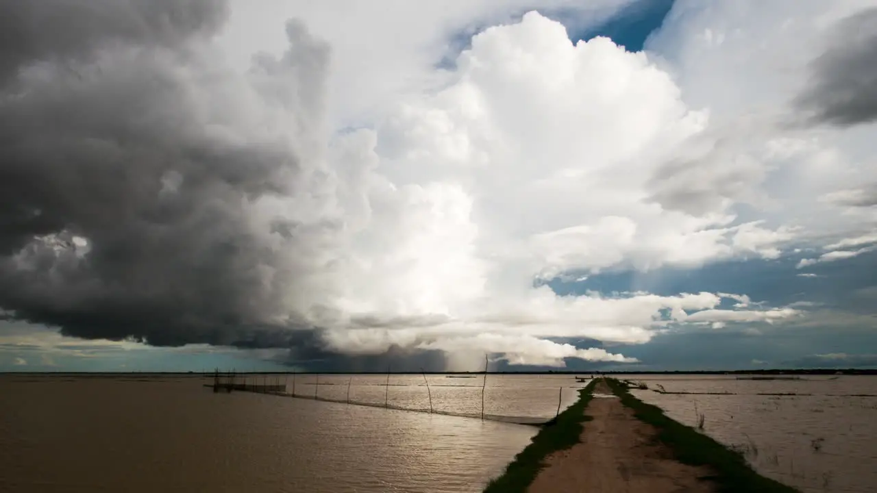 Low lying stormy weather front clouds rolling horizontally over the Tonle Sap lake with fish nets in foreground and moving rain as the south east Asia monsoon season sets in