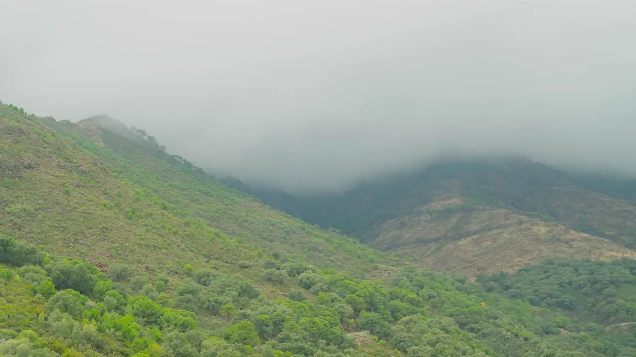 Fog and dark clouds flowing above mountains of Estepona time lapse view